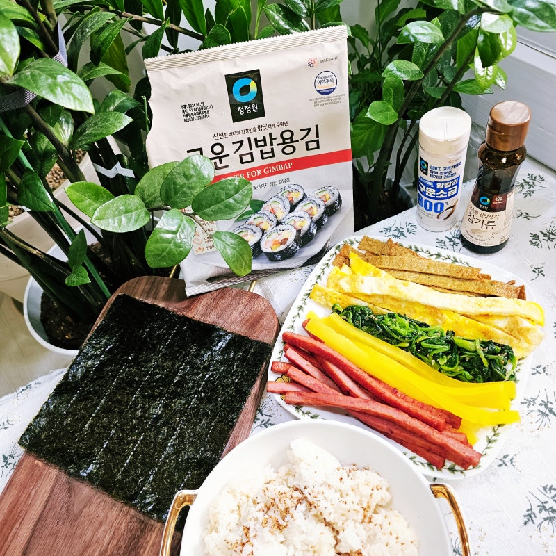 Kimbap ingredients laid out -- cooked rice, seaweed sheets, carrot, spinach, egg, ham, sesame oil, salt