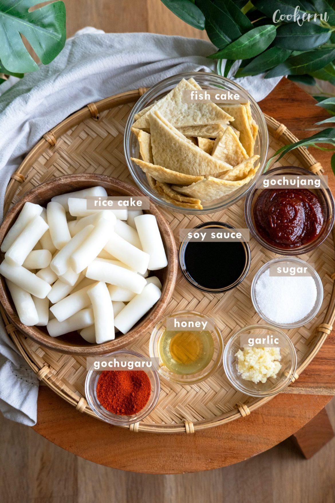 Tteokbokki ingredients laid out -- rice cakes, fish cakes, gochujang paste, green onion, sugar, water