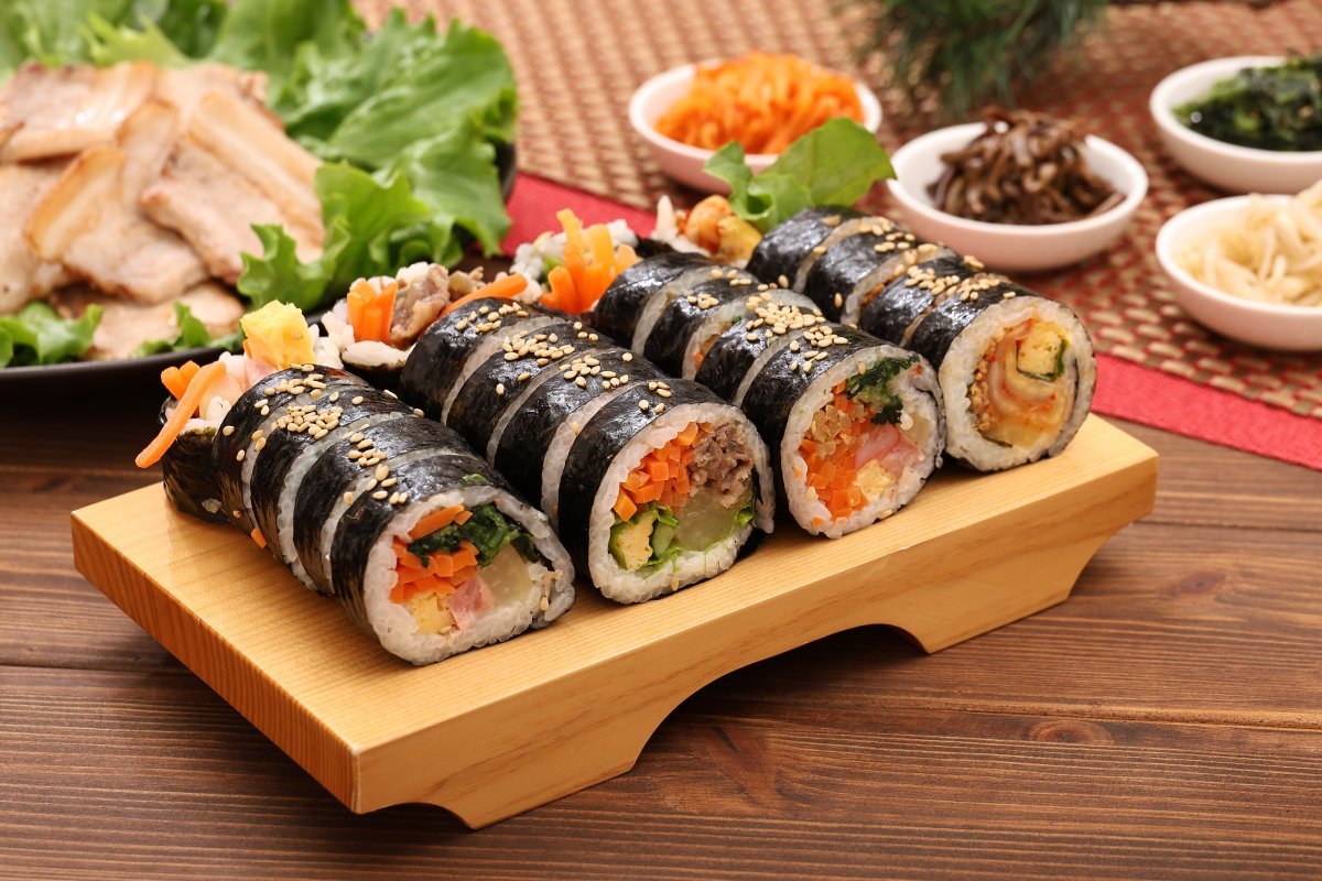 Kimbap - Korean seaweed rice rolls sliced neatly on a wooden board with colorful fillings